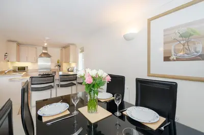 a dining room with a table with a vase of flowers at Russell Court 2 - Beautifully furnished modern apartment with parking and views over Looe river and town in Looe