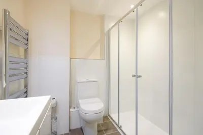 a white bathroom with a toilet and a shower at Russell Court 2 - Beautifully furnished modern apartment with parking and views over Looe river and town in Looe