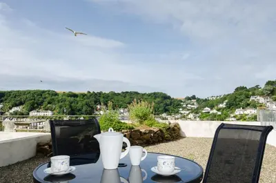 a table with two chairs and a vase on it at Russell Court 2 - Beautifully furnished modern apartment with parking and views over Looe river and town in Looe