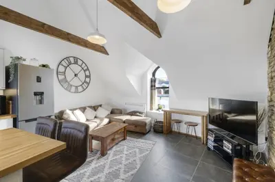 a living room with a couch and a clock on the wall at Stylish Apartment Sea Views Central Newquay in Newquay