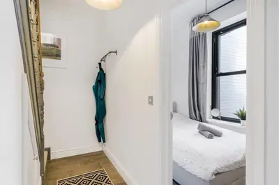 a hallway with a mirror and a bed in a room at Stylish Apartment Sea Views Central Newquay in Newquay