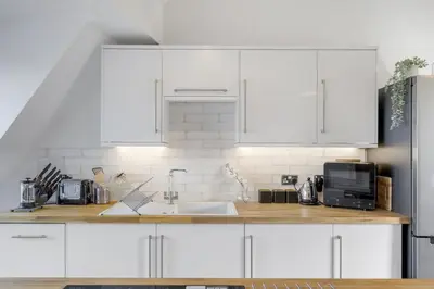 a kitchen with white cabinets and a sink at Stylish Apartment Sea Views Central Newquay in Newquay