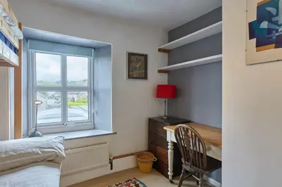 a bedroom with a bed and a desk and a window at Cornish Cottage St Agnes free parking and garden in St. Agnes