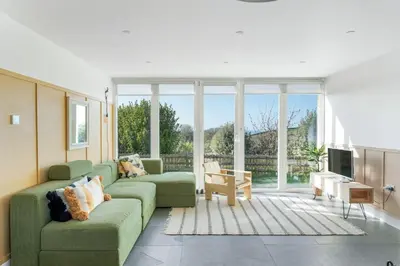 a living room with two green couches and a tv at Beach Life Cabin Vibes Ocean Views nr Bude in Bude