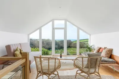 a living room with a table and chairs and a large window at Beach Life Cabin Vibes Ocean Views nr Bude in Bude