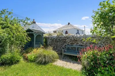 a garden with a bench and a stone wall at Beach Life Cabin Vibes Ocean Views nr Bude in Bude