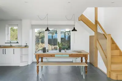 a kitchen and dining room with a wooden table at Beach Life Cabin Vibes Ocean Views nr Bude in Bude