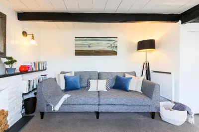 a couch in a living room with blue and white pillows at Listed Fisherman's Cottage Mevagissey Sea Views in Mevagissey