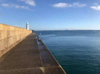 a lighthouse on the side of a wall near the water at Listed Fisherman's Cottage Mevagissey Sea Views in Mevagissey