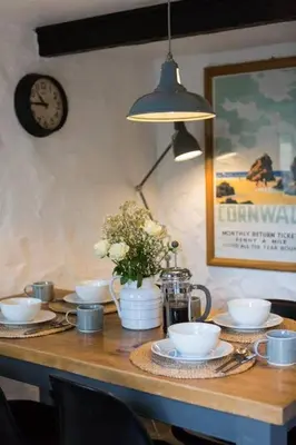 a wooden table with plates and cups and a clock at Listed Fisherman's Cottage Mevagissey Sea Views in Mevagissey
