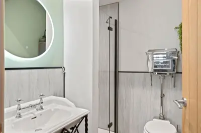 a bathroom with a sink and a toilet and a mirror at Scandi Style Apartment in Central Falmouth in Falmouth