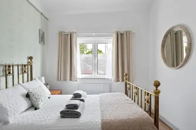 a white bedroom with a bed with a mirror at Scandi Style Apartment in Central Falmouth in Falmouth