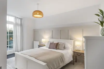 a white bedroom with a white bed and a window at Cosy Cottage nr Bodmin Moor Private Parking in Helland