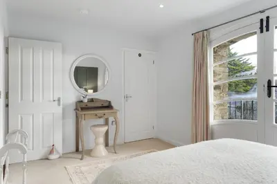 a white bedroom with a mirror and a bed at Cosy Cottage nr Bodmin Moor Private Parking in Helland