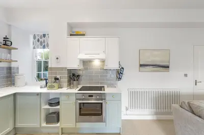 a kitchen with white cabinets and a stove top oven at Cosy Cottage nr Bodmin Moor Private Parking in Helland
