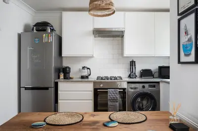 a kitchen with a wooden table and a refrigerator at Stylish Apartment Garden with Beautiful Sea Views in Newquay