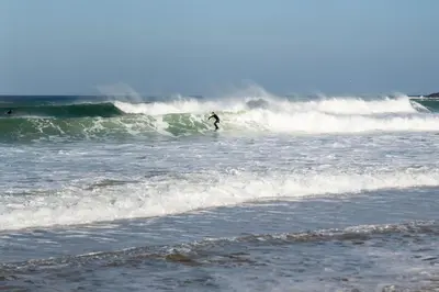 a man riding a wave on a surfboard in the ocean at Stylish Apartment Garden with Beautiful Sea Views in Newquay
