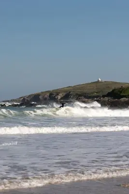 a person riding a wave on a surfboard in the ocean at Stylish Apartment Garden with Beautiful Sea Views in Newquay
