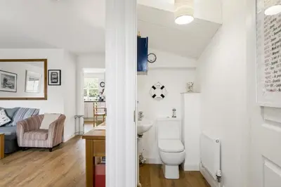 a bathroom with a toilet and a living room at Homely Cottage & Garden nr Fowey Private Parking in Par