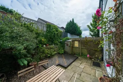 a garden with a wooden bench and a fence at Homely Cottage & Garden nr Fowey Private Parking in Par
