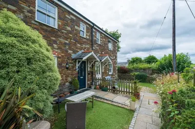 a brick house with a bench in the front yard at Homely Cottage & Garden nr Fowey Private Parking in Par