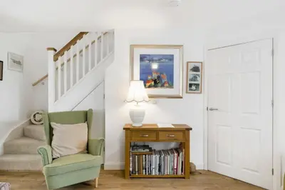 a living room with a green chair and a staircase at Homely Cottage & Garden nr Fowey Private Parking in Par