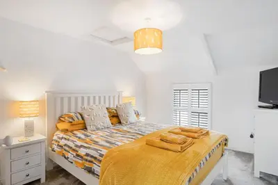 a bedroom with a bed with a yellow blanket and a tv at Beautiful Cottage Minutes from Mevagissey Harbour in Mevagissey