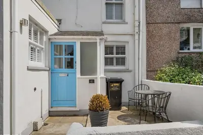 a blue door of a house with a table and chairs at Beautiful Cottage Minutes from Mevagissey Harbour in Mevagissey