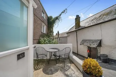 a patio with two chairs and a table on a balcony at Beautiful Cottage Minutes from Mevagissey Harbour in Mevagissey