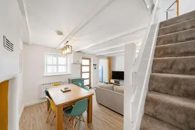a living room with a table and a staircase at Beautiful Cottage Minutes from Mevagissey Harbour in Mevagissey