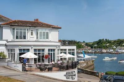 a restaurant with tables and umbrellas next to a body of water at Stylish Apartment in Falmouth nr Seafront in Falmouth