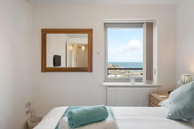 a bedroom with a mirror and a bed and a window at Modern Mews Home with Sea Views Private Parking in Newquay