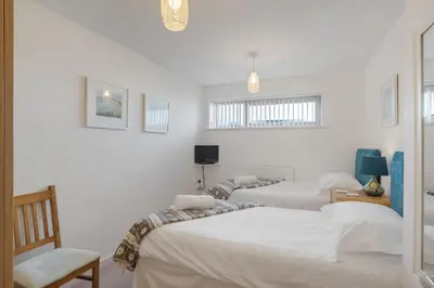 two beds in a room with white walls at Modern Mews Home with Sea Views Private Parking in Newquay