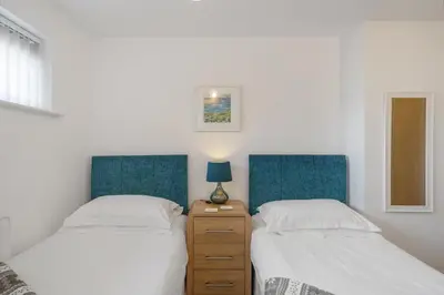 a bedroom with two beds and a dresser with a lamp at Modern Mews Home with Sea Views Private Parking in Newquay