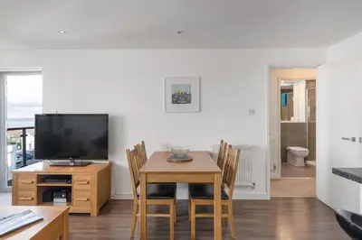 a dining room with a table and a television at Modern Mews Home with Sea Views Private Parking in Newquay