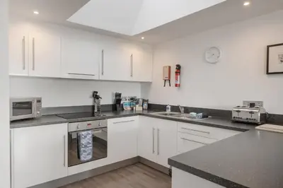 a kitchen with white cabinets and a counter top at Modern Mews Home with Sea Views Private Parking in Newquay