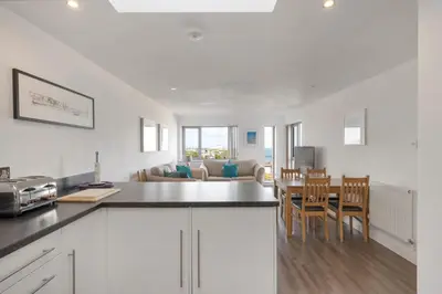 a kitchen with white cabinets and a table and chairs at Modern Mews Home with Sea Views Private Parking in Newquay