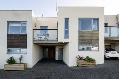 a white house with a car parked in front of it at Modern Home with Sea Views Newquay in Newquay