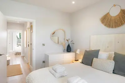 a white bedroom with a bed and a mirror at Contemporary Townhouse with Sea Views & Parking in Newquay