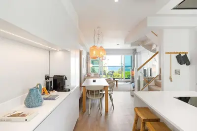 a kitchen with white counters and a dining room at Contemporary Townhouse with Sea Views & Parking in Newquay