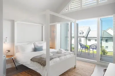 a white bedroom with a bed and a large window at Contemporary Townhouse with Sea Views & Parking in Newquay