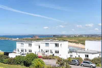 a white house with cars parked in front of a beach at Contemporary Townhouse with Sea Views & Parking in Newquay