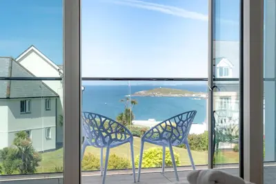 two chairs sitting on a balcony looking out at the ocean at Contemporary Townhouse with Sea Views & Parking in Newquay