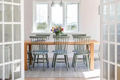 a dining room table with chairs and a vase of flowers at Stunning House with Estuary Views Padstow in Padstow