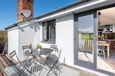 a patio with a table and chairs on a balcony at Stunning House with Estuary Views Padstow in Padstow