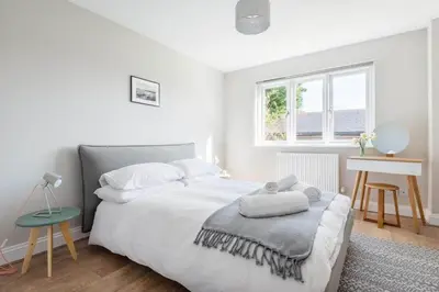 a white bedroom with a bed and a table at Stunning House with Estuary Views Padstow in Padstow