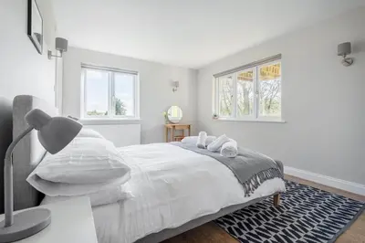 a white bedroom with a bed and two windows at Stunning House with Estuary Views Padstow in Padstow