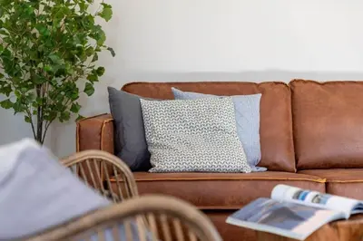 a brown couch with blue pillows and a table at Stunning House with Estuary Views Padstow in Padstow