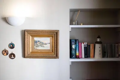 a picture on a wall next to a shelf with books at Smugglers Cottage in Penryn Nr Falmouth in Penryn