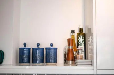 a shelf with bottles of alcohol and other items at Smugglers Cottage in Penryn Nr Falmouth in Penryn